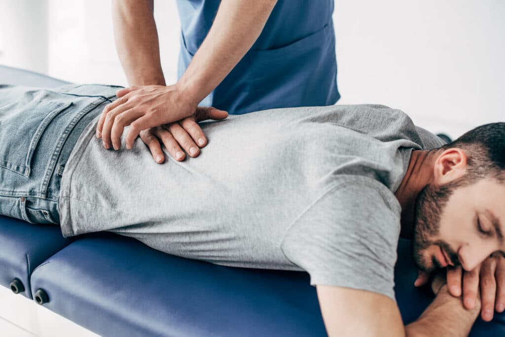 chiropractor massaging back of man on Massage Table in hospital