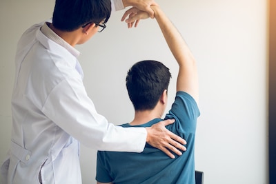 chiropractor-stretching-a-young-man-arm-in-medical-office