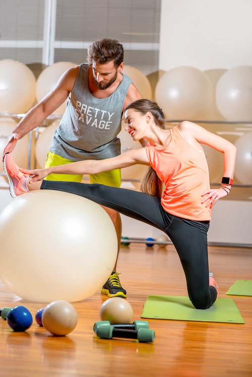 Woman exercising with fitball with a personal trainer